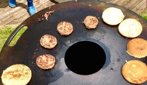 Burger-Grillen auf Feuerplatte und Feuertonne, Fleisch und Brötchen